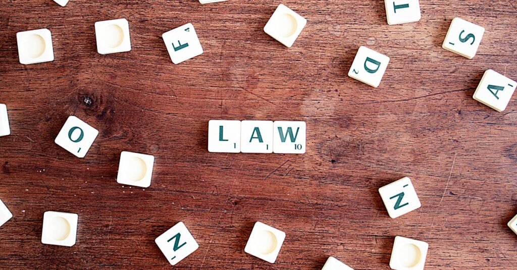 pexels-photo-613508-613508 Scrabble tiles spelling 'LAW' on a wooden table, symbolizing connections to education and legality.